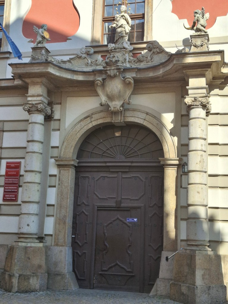Decorative entrance door with ornate stone architecture, featuring statues and decorative elements above the door.